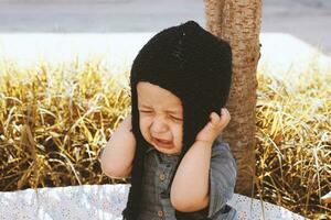 Unhappy 2-3 years old child crying in autumn garden photo