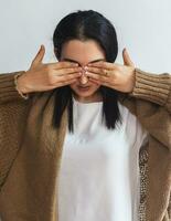 Portrait of young attractive girl covering her eyes with two palms. Beautiful brunette woman closing eyes with hands. I can't see you photo