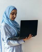 Young Arabian Muslim woman in hijab holding laptop pc computer photo