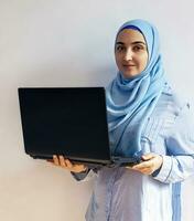 Young Arabian Muslim woman in hijab holding laptop pc computer photo