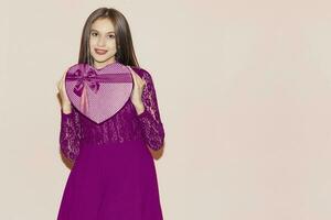 Happy young girl holds heart shaped giftbox. Valentines day, birthday, womens day, anniversary, holiday celebration concept photo