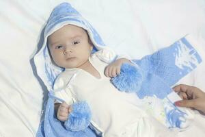 hermosa recién nacido bebé en blanco cama con blanco antecedentes vistiendo azul sombrero o paño foto