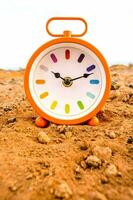 an orange alarm clock sitting on a dirt field photo