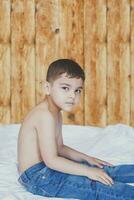 Happy childhood concept. 6 years old boyhaving good time. Cute little kid sitting on comforter photo