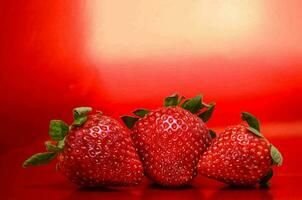 three strawberries on a red background photo