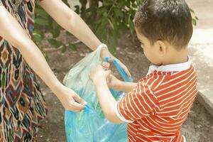 Mother and son collecting plastic bottles. Family carry garbage bag. Plastic pollution on land. photo