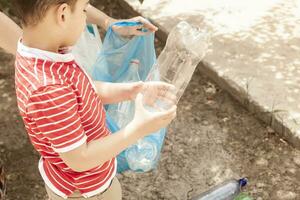 Mother and son collecting plastic bottles. Family carry garbage bag. Plastic pollution on land. photo