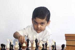 Thoughtful boy playing chess. A little middle eastern boy plays chess. Thinking on find the best move photo