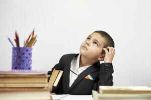 Thoughtful schoolboy scratching head and thinking on new ideas photo