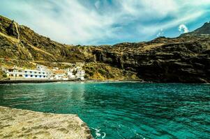 the blue water of the ocean and a small village on the coast photo