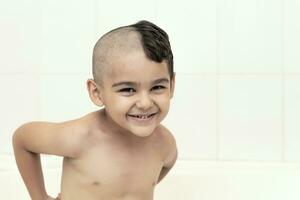 Six-year boy at haircutting at home. Father cut half of the son's hair off at the bathroom photo