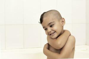 Six-year boy at haircutting at home. Father cut half of the son's hair off at the bathroom photo