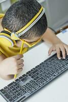 Homeschooling. Cute schoolboy in yellow learning foreign language online photo