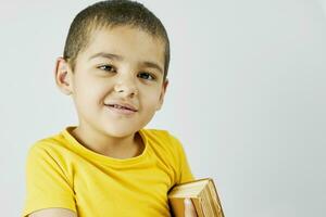 Little genius boy in yellow carrying a big book photo