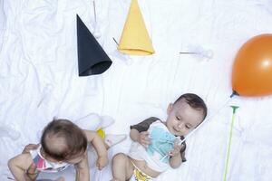 Two babies playing with balloons and birthday caps. Brother and sister playing together photo