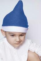 A little kid making a funny annoyed face. Annoyed Christmas Boy in Santa Hat. A really serious and handsome kid photo