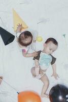 Two babies playing with balloons and birthday caps. Brother and sister playing together photo