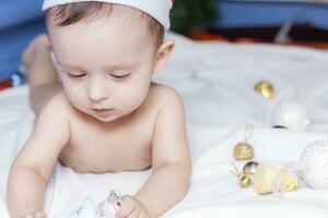 Baby boy playing with christmas balls and toys photo