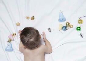 Baby boy playing with christmas balls and toys photo