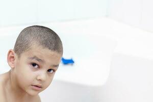 Boy takes a bath. 5-6 years kid having water fun in bathroom. photo
