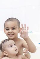 Two brothers having water fun in bath photo