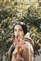 Fall season concept. Beautiful middle-eastern woman holds an yellow autumn leaf photo