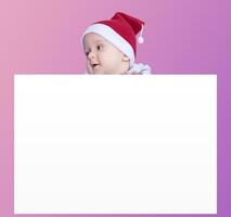 un pequeño chico con Papa Noel gorra participación el blanco papel. Papa Noel bebé chico con un vacío blanco tarjeta. Copiar espacio para tu publicidad y texto foto