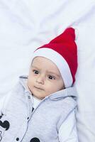 pequeño Papa Noel. 1 año antiguo bebé chico en Papa Noel claus gorra. Navidad niños foto