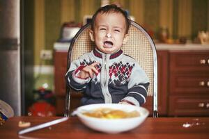 llorando bebé chico. enojado pequeño niño en el cocina foto