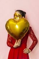 Woman wearing masquerade mask and holding heart shaped air ballon. Valentines Day, Birthday, Anniversary, Festive, Ball celebration concepts photo