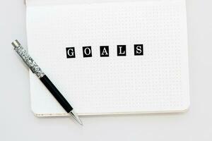 Filling in the diary, writing Goals in a notebook in a dot photo