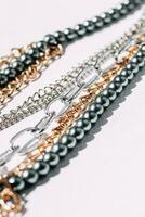 A necklace of gray beads with chain decorations on a white aesthetic background. photo