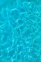 Azure transparent texture of water in a blue pool with splashes from the sun photo