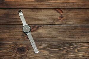 Wrist stylish watch with black dial on the table with brown planks. photo
