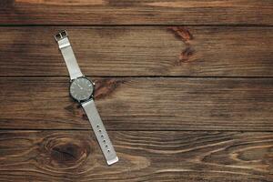 Wrist stylish watch with black dial on the table with brown planks. photo