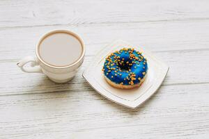 Coffee in a cup with a saucer with a donut in blue-yellow color. photo