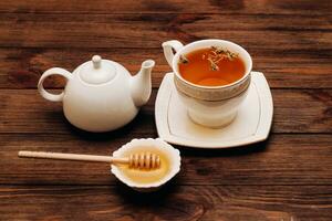 Liquid fresh linden honey in a plate with a wooden honey spoon and tea. photo