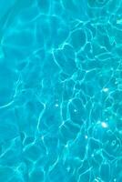 Azure transparent texture of water in a blue pool with splashes from the sun photo