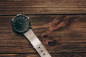 Wrist stylish watch with black dial on the table with brown planks. photo