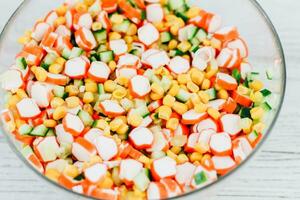 Salad from crab sticks, corn and fresh cucumber photo