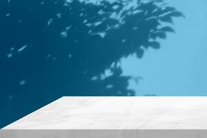 Minimal White Marble Table Corner with Light Beam, Shadow, and Spotlight on Blue Concrete Wall Background, Suitable for Product Presentation Backdrop, Display, and Mock up. photo