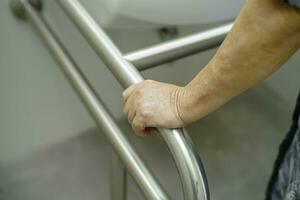 Asian elderly woman patient use toilet bathroom handle security in nursing hospital, healthy strong medical concept. photo