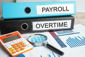 Payroll, Overtime. Binder data finance report business with graph analysis in office. photo