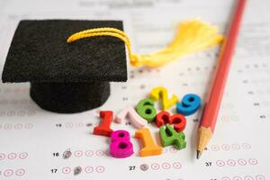 Graduation gap hat and pencil on answer sheet paper, Education study testing learning teach concept. photo