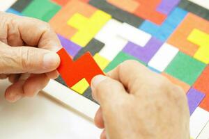 Asian elderly woman playing puzzles game for treatment dementia prevention and Alzheimer disease. photo