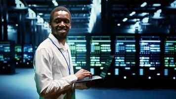 African american engineer inspecting interlinked computers creating server network. High tech facility using parallel computing to perform complex calculations and process large amounts of data photo