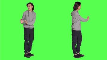 Person pretending to push thing aside, expressing rejection or denial in studio. Young adult mimicking refusal over isolated full body greenscreen background, stop symbol on camera. video