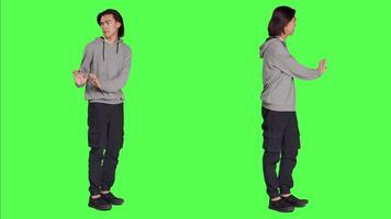 Person pretending to push thing aside, expressing rejection or denial in studio. Young adult mimicking refusal over isolated full body greenscreen background, stop symbol on camera. video