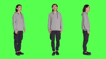 Cheerful male model laughing in studio, posing and being positive against full body greenscreen backdrop. Asian man smiling in studio, showing amusing funny expressions, relaxed guy. video