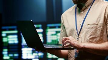 Computer scientist using laptop to check data center security to make sure virus protection software is up to date and hackers trying to penetrate systems are denied, close up photo